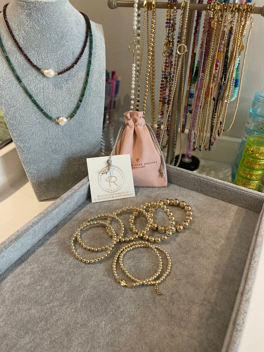 Stunning stack! Left to right - two 5mm 14k gold filled bracelets, 6mm 14k gold filled bracelet, 8mm 14k gold filled bracelet, 10mm 14k gold filled bracelet, 3mm  14k gold filled bracelet with 3 hearts and 3mm 14k gold filled bracelet with "L" initial charm.
