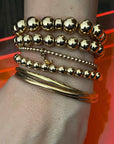 Top to bottom - 10mm 14k gold filled bracelet with rondelles, 8mm 14k gold filled bracelet, 3mm 14k gold filled bracelet with "J" initial charm, 6mm 14k gold filled bracelet. Bangles are clients own.